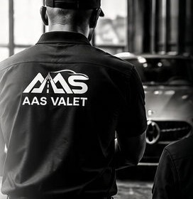 The back of an AAS Valet uniform, with the mark and a guest car behind.